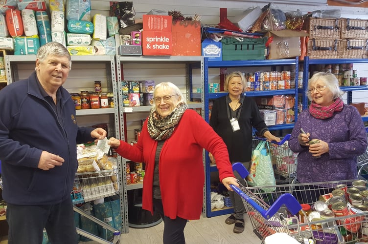 Richard Balchin of Woolmer Forest Lions Club presents a £500 cheque to Heather Ford and two of her volunteers at the Bordon food bank