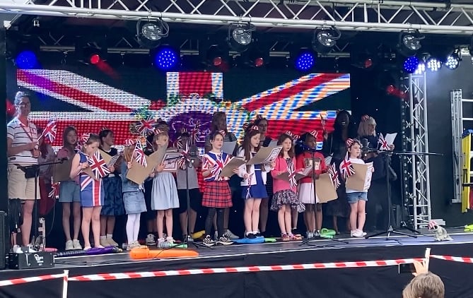 Woodlea School Choir and Cllr Bisi Kennard sing the national anthem during the Whitehill & Bordon Platinum Jubilee music festival at Mill Chase Recreation Ground in Bordon on June 3rd 2022.