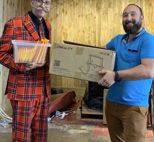 Stuart Morrison, left, gives a 3D printer to Paul Jones.