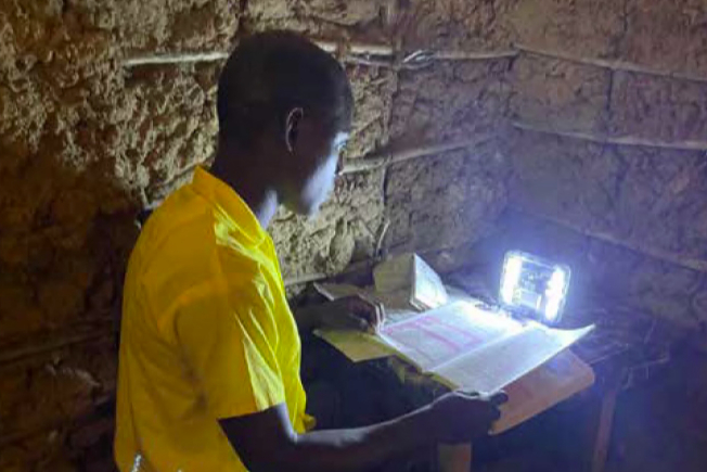 A pupil from Menzamwenye School in rural Kenya studying at home with a Mwezi light.