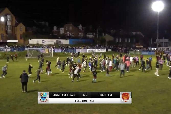 The crowd rush onto the pitch after Farnham Town seal a memorable cup win at the Memorial Ground