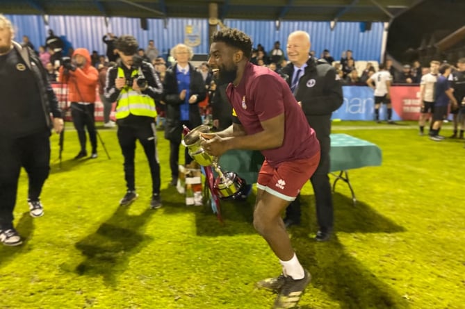 Farnham Town's Lamar Koroma lifts the Southern Combination Cup after Wednesday night's dramatic final victory