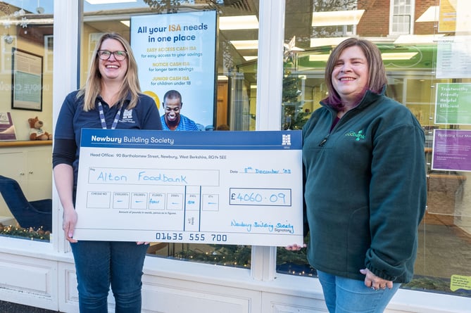 Julie Harness of Newbury Building Society, left, gives a cheque to Sian Mills of Alton Foodbank at Newbury Building Society, Alton, December 2023.    