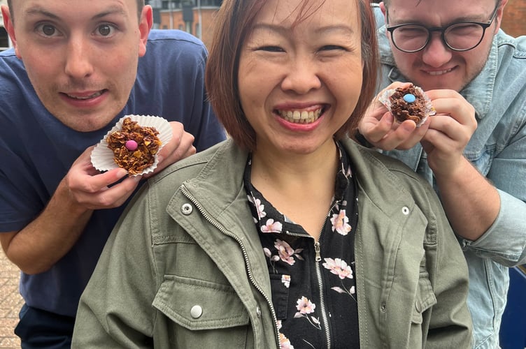 Luke Bateman and Elliott Williams tempt Chariya Khattiyot with their cornflake cakes, Market Square, Alton, December 2023.