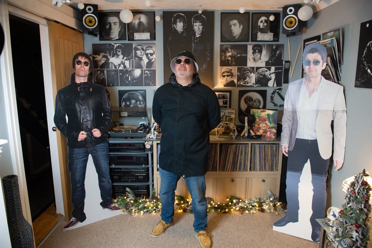 Oasis superfan John Smallbones pictured at home in Hampshire. See SWNS story SWOCoasis; Meet the Oasis superfan who has spent THOUSANDS on band memoribillia including life size cut outs of the Gallagher brothers - and his fiancee isn't even a fan. John Smallbones, 45, fell in love with the band back in 1992 and was devastated when the brothers went their separate ways. Over the past decade, window surveyor John has spent thousands of pounds on Oasis merchandise including vinyls, clothing and life size cutouts of both Gallagher brothers. He's even got Oasis tattoos and has named his business 'Wall of Glass' after the popular 2017 Liam Gallagher hit with a van plastered in stickers dedicated to the boys. His home is covered top to bottom with Oasis memorabilia, much to the amusement of his extremely patient fiancee Elaine, 46, who isn't even a fan of the band.