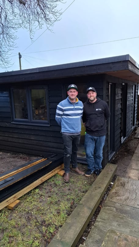 Tom Chapman and Laurence Nicholls outside a cabin they are building in Tom's garden.